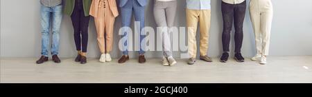 Cropped image of legs of people standing in a row near the wall waiting for an interview. Stock Photo