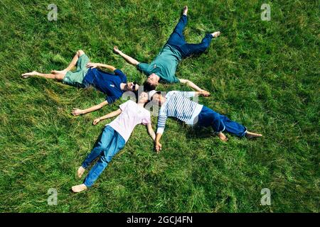Group of friends lying on grass in a circle Stock Photo