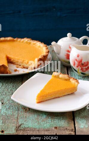 Homemade yummy pumpkin pie and teaware on old table painted blue vertical Stock Photo