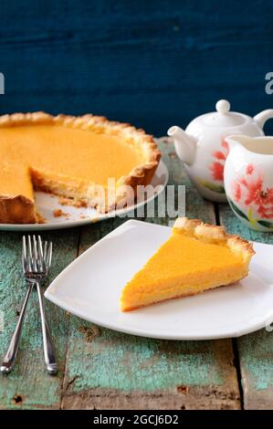 Homemade bright pumpkin pie and teaware on shabby wooden table vertical Stock Photo