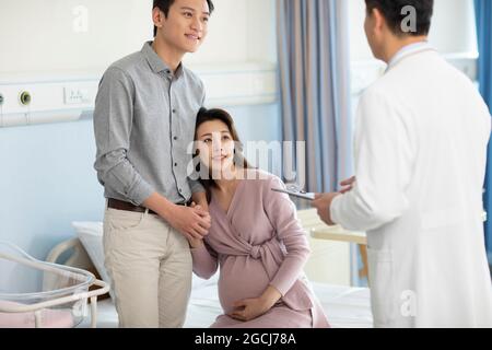 Pregnant woman talking with doctor in hospital ward Stock Photo