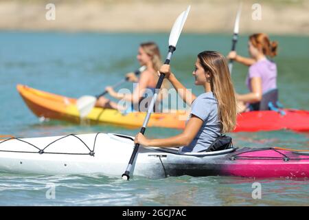 Group of friends rowing in kayaks in a lake on summer vacation Stock Photo