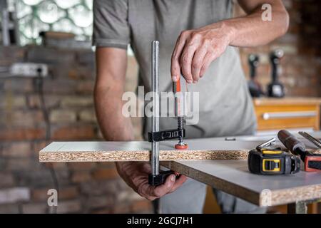 Carpenter doing wood work using clamping hand tool in his workshop. Stock Photo