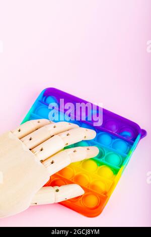 Pop it toy and artificial hand on pink background. Robot clicks on pop it. Anti-stress concept. Copy space. Top view Stock Photo