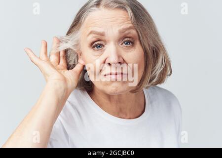 elderly woman in white t-shirt pain health problems dissatisfaction treatment Stock Photo