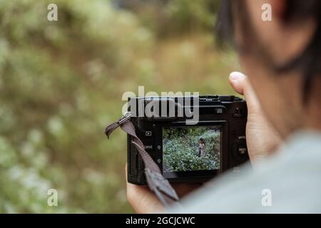 Selective focus of digital camera with photo of handsome model in flower field Stock Photo