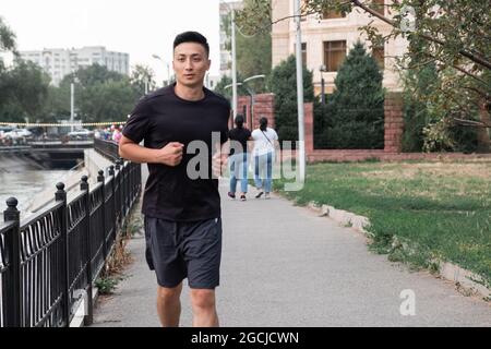 An Asian man running in the city, in the evening. Kazakhstan Stock Photo