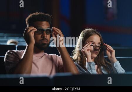Cheerful young couple with 3d glasses in the cinema, talking. Stock Photo