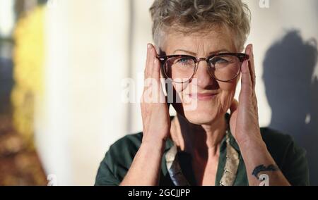 Portrait of senior woman standing outdoors in town, looking at camera. Stock Photo