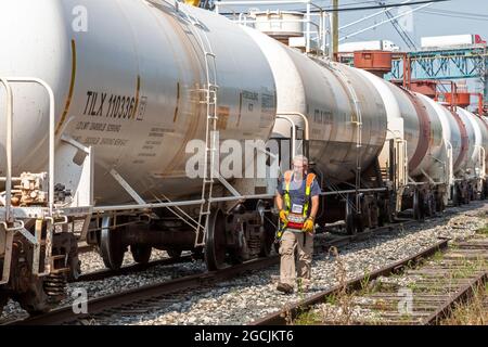Detroit, Michigan - Railroad chemical tank cars near downtown Detroit. Wearing a remote control vest, a worker controls the movement of the train as h Stock Photo