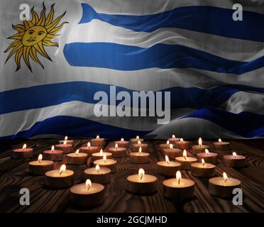 Mourning candles burning on Uruguay national flag of background. Memorial weekend, patriot veterans day, National Day of Service Remembrance. Burning Stock Photo