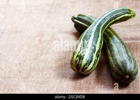 Fresh striped zucchini on sackcloth background with copy space. Rustic style Stock Photo