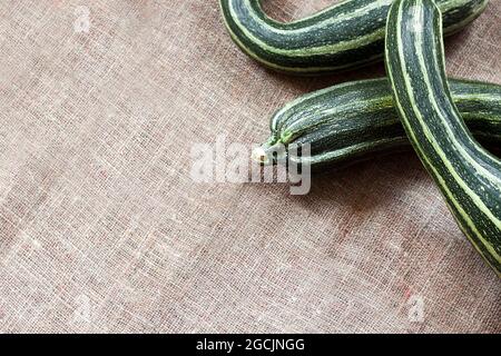 Fresh striped zucchini on sackcloth background with copy space Stock Photo