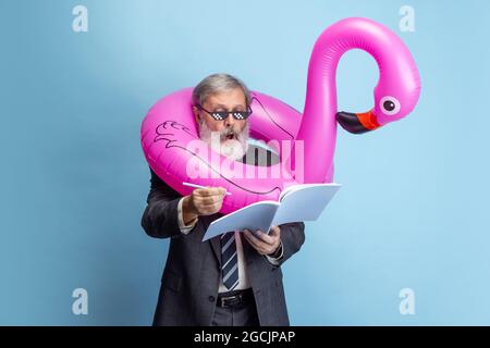 Portrait of elder gray-headed man, professor, teacher working isolated on blue studio background. Concept of professional occupation, job, education Stock Photo