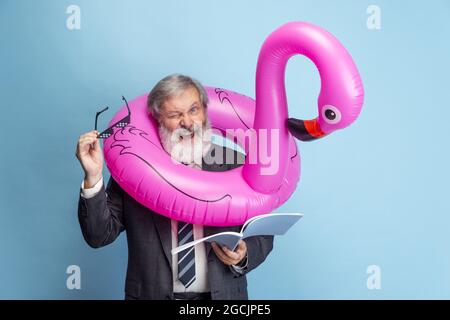 Portrait of elder gray-headed man, professor, teacher working isolated on blue studio background. Concept of professional occupation, job, education Stock Photo