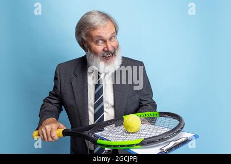 Portrait of elder gray-headed man, professor, teacher working isolated on blue studio background. Concept of professional occupation, job, education Stock Photo