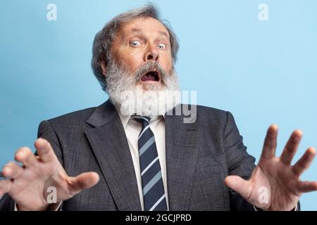 Crazy professor, teacher, gray-headed bearded man posing isolated on gray studio background. Concept of professional occupation, job, education, funny Stock Photo