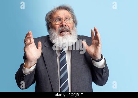 Crazy professor, teacher, gray-headed bearded man posing isolated on gray studio background. Concept of professional occupation, job, education, funny Stock Photo