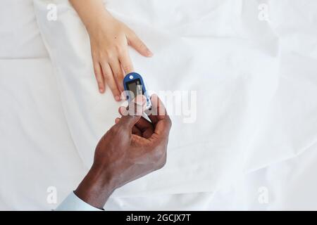 Closeup of male doctor checking oxygen levels of child in hospital using oximeter, copy space Stock Photo