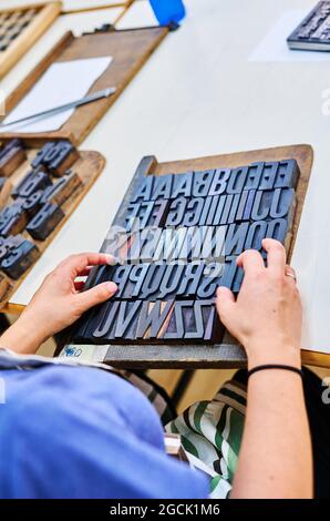 From above of anonymous male worker working with letterpress alphabet on wooden board in workshop Stock Photo
