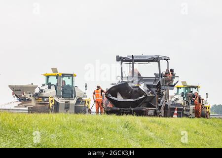 Rheden, The Netherlands - August 3, 2021: Asphalt paving crew using heavy machinery repaving a Dutch highway between Arnhem and Zutphen in Rheden, The Stock Photo