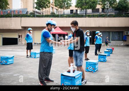 (210809) -- ZHANGJIAJIE, Aug. 9, 2021 (Xinhua) -- Delivery man Yan Yingzhao (2nd L) gets his hands disinfected before fulfilling delivery orders in Yongding District of Zhangjiajie, central China's Hunan Province, Aug. 9, 2021.  Since last Tuesday, all the people in the central Chinese city of Zhangjiajie, including residents and tourists, are not allowed to leave the city as part of efforts to curb the latest resurgence of COVID-19.   Local authorities have prioritized delivery services to ensure the supply of necessities. Couriers like 22-year-old Yan Yingzhao are working day and night to de Stock Photo