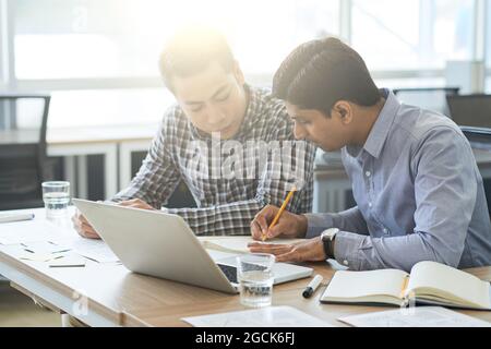 Multi-ethnic business team discussing documents with interface layouts at meeting Stock Photo