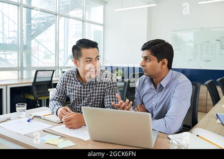 Multi-ethnic team of UX designers discussing interface of new monile application they are working on Stock Photo