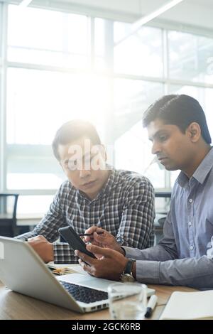Mobile app developer meeting with UX designer when they are discussing and testing new interface for application on smartphone Stock Photo