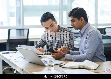 Project manager and UX designer checking work of new interface when using application on smartphone Stock Photo