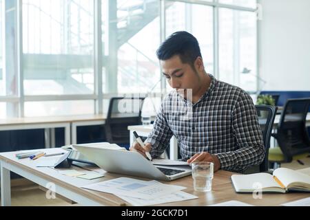 Serious young UI designer working on new project at his office desk, he is drawing sketch of website interface Stock Photo