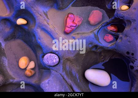 From above of textured background of assorted colorful pebbles placed on rock in water Stock Photo