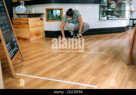 Coffee shop worker putting floor marks Stock Photo