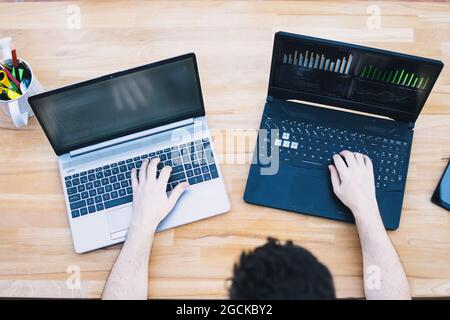 Man trading cryptocurrencies using two laptops Stock Photo