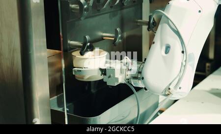 Robot with artificial intelligence making coffee on coffee machine. Close up shot Stock Photo