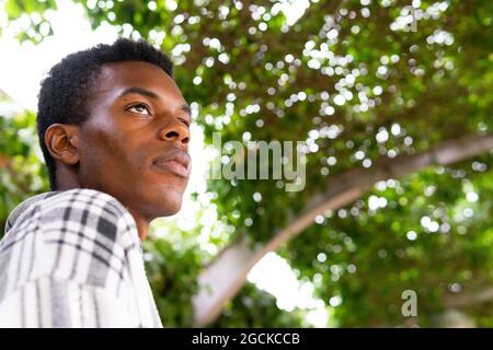 From below side view unemotional African American stylish male standing in the city looking away Stock Photo
