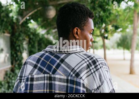 Back view unemotional African American stylish male standing in the city looking away Stock Photo