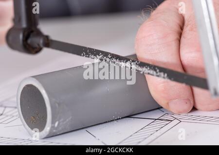 Plumber sawing a pvc pipe, closeup Stock Photo