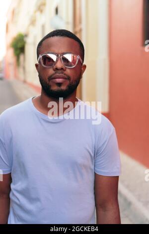 Portrait of stylish Black man walking with sunglasses outdoors. Fashionable black man in the street. Stock Photo
