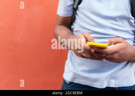 African man with smart phone next to a red wall Stock Photo