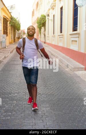 Smiling man with backpack looking upward while standing outdoors Stock Photo