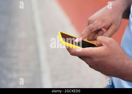 Black man using smart phone against red wall Stock Photo