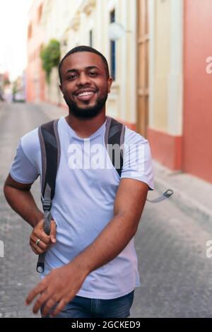 African man carrying backpack while walking in city Stock Photo