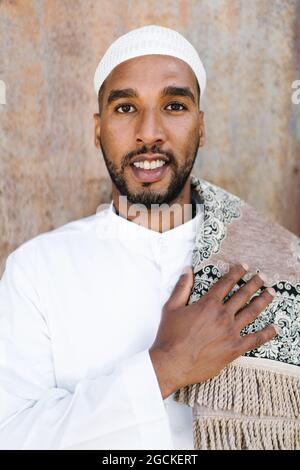 Islamic male in authentic white clothes while standing against grungy wall Stock Photo
