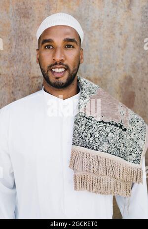 Islamic male in authentic white clothes while standing against grungy wall Stock Photo