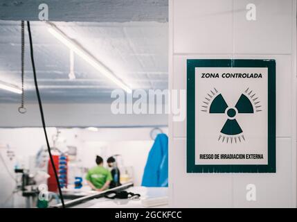 Warning sign of danger radioactive zone hanging on wall near entrance of X ray laboratory in vet clinic with people working inside Stock Photo