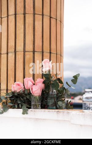 Pink roses inside glass vases placed on terrace outdoors Stock Photo