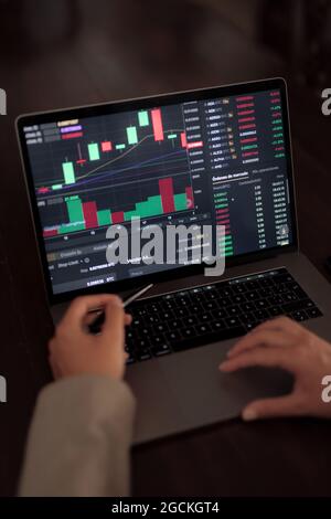 High angle of crop anonymous trader using netbook while analyzing chart on binary option Stock Photo