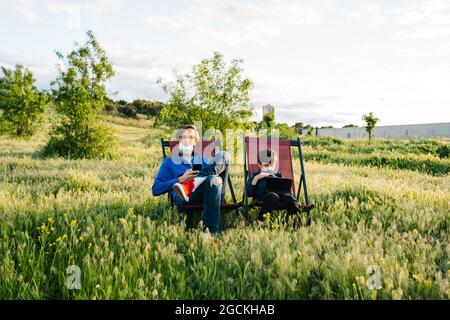Father and son relaxing in folding hammocks in the middle of the mountain at sunset Stock Photo