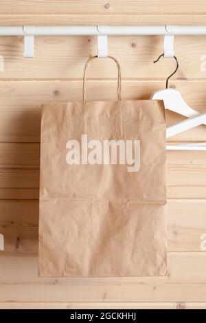 A paper bag hangs near white hangers in an empty wooden room, front view background photo Stock Photo